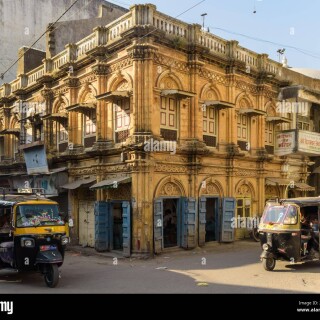 junagadh-gujarat-india-december-2018-a-beautiful-yellow-building-with-arcaded-windows-and-vintage-wooden-doors-in-the-old-market-area-2B19TH3
